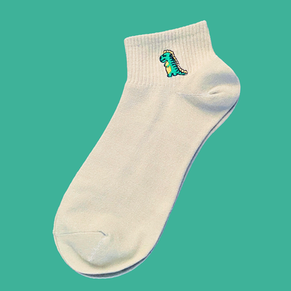 White ankle sock with a dinosaur design on a teal background