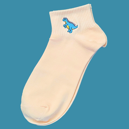 Beige ankle sock with a blue dinosaur design on a teal background