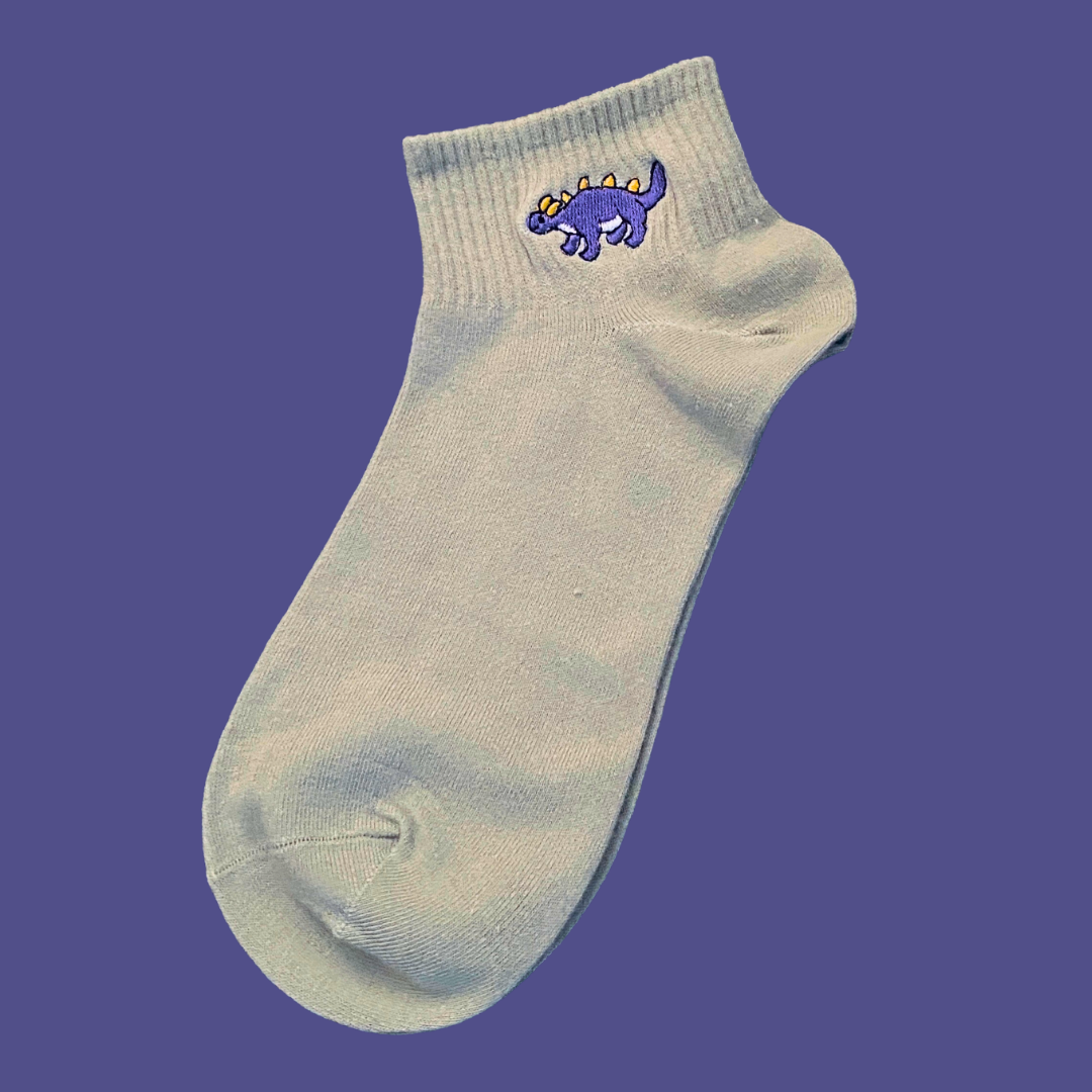Light gray ankle sock with a blue dinosaur design on a purple background