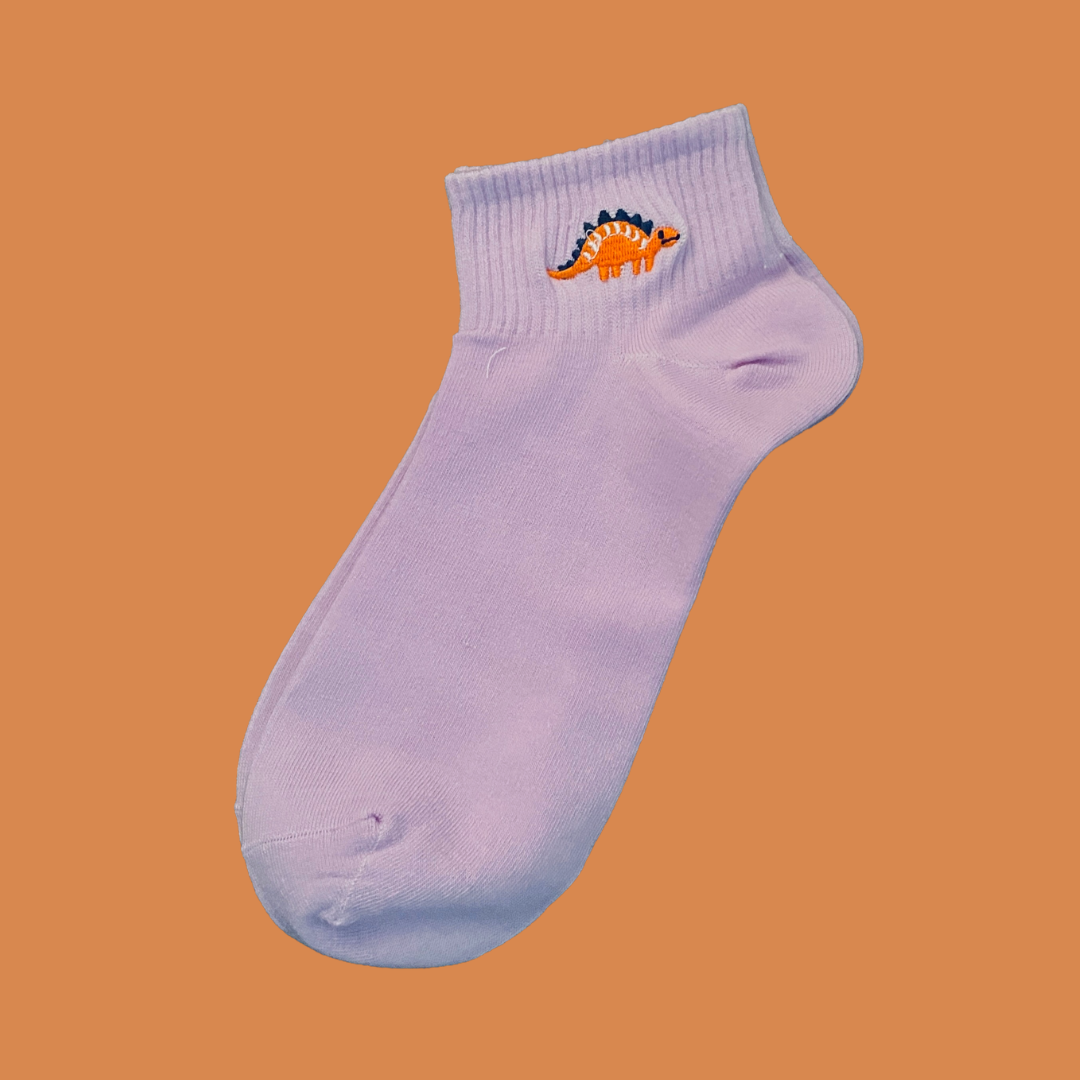 Light purple ankle sock with a dinosaur design on an orange background