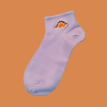 Light purple ankle sock with a dinosaur design on an orange background